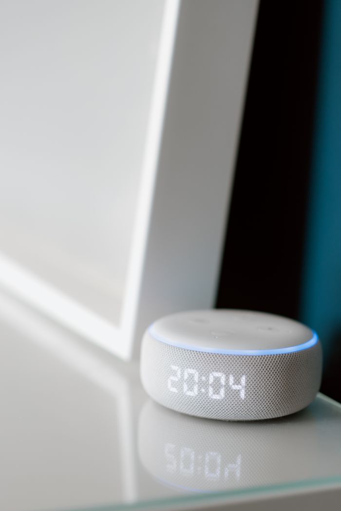 首页 Close-up of a smart speaker with digital time display indoors.